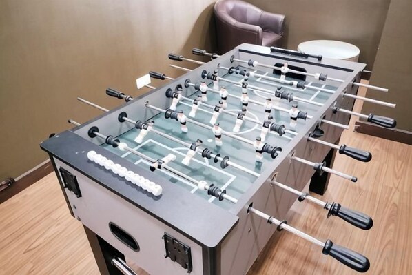 A foosball table with a standard layout, including a netted playing area and multiple rods with handles.