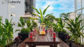 A wooden table with cans of beer and a yellow bag, surrounded by potted plants. - Cubicity Ton That Tung (Ho Chi Minh City)