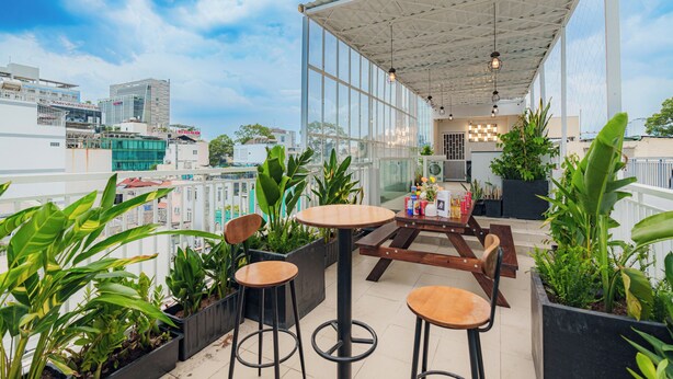A rooftop terrace with a covered seating area, potted plants, and a view of the cityscape. - Cubicity Ton That Tung (Ho Chi Minh City)