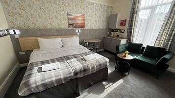 Una habitación de hotel con cama, kitchenette pequeña, sofá y mesa de comedor.