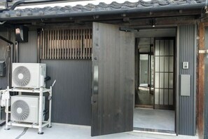 A building entrance with a sliding door, two air conditioning units, and a metal gate. - Trive Kamejima (Nagoya)