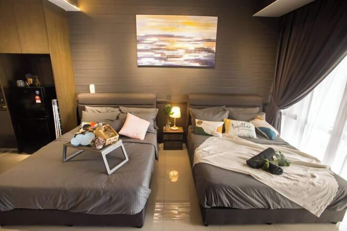 A hotel room with two beds, a nightstand with a lamp, a painting on the wall, and a view of the outdoors.