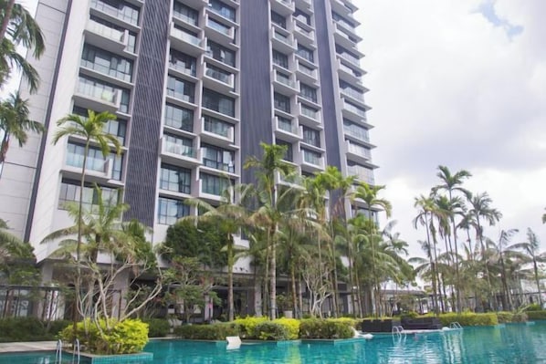 Un hotel de gran altura con varios pisos, una piscina y palmeras.