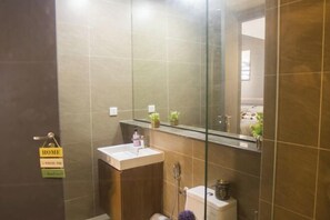 Une salle de bain moderne avec une douche à parois de verre, un lavabo blanc et des toilettes. On y trouve une petite étagère avec des plantes et un miroir au-dessus du lavabo.