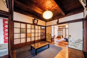 A traditional Japanese room with tatami flooring, a low wooden table, sliding doors, and a hanging light fixture. - Ranjatai (Nara)