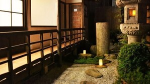 A traditional Japanese garden with a wooden walkway, stone lantern, and a well-maintained bonsai tree. - Ranjatai (Nara)