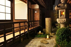 Un giardino tradizionale giapponese con una passerella in legno, un farolino in pietra e un bonsai curato.