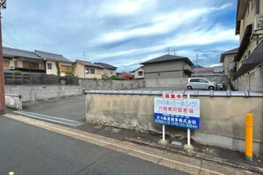 Un quartier résidentiel avec un mur en béton, un panneau indicateur et une voiture garée.