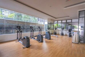 Une salle de sport équipée de machines de cardio, dotée de grandes fenêtres et d’un plancher en bois.