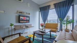 Een moderne woonkamer met een bank, fauteuils, een salontafel en een aan de muur bevestigde televisie.