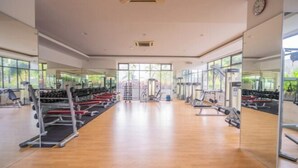 Een sportschool met spiegelwanden, diverse fitnessapparaten en grote ramen.