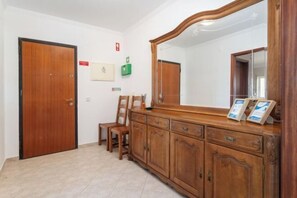 Un pasillo con una puerta de madera, un espejo y un aparador de madera con cajones.
