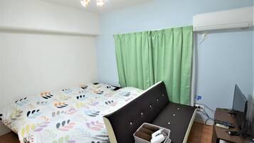 Un dormitorio con una cama, un escritorio, una computadora y una cortina verde.