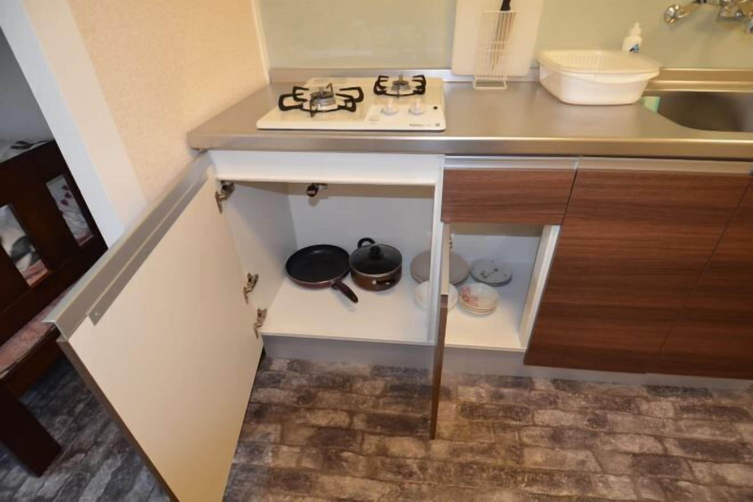 Una cocina compacta con estufa a gas, un estante con utensilios de cocina y un lavamanos.