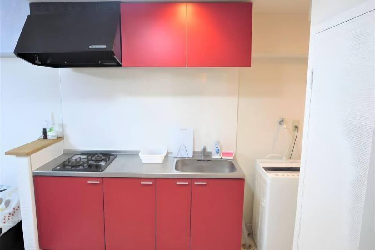 Une cuisine équipée d’une cuisinière à gaz, d’un évier et d’un meuble rouge.