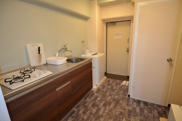 A compact kitchen with a gas stove, sink, and a small countertop. - Comfort CUBE PHOENIX Miyazaki (Miyazaki)