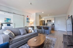 Un salon moderne avec un canapé, une table basse et un coin cuisine à l’arrière-plan.