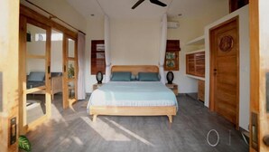 A bedroom with a bed, wooden doors, a ceiling fan, and a view of the outside. - 1BR Villa with Private Pool in Amed (Bali)