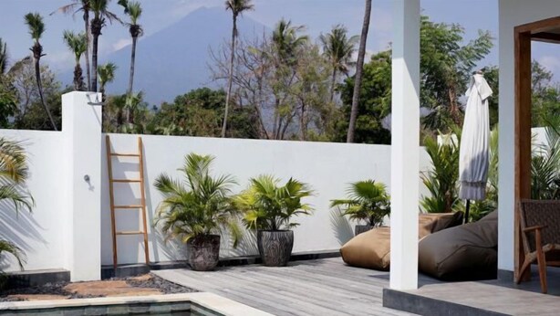 A pool area with a wooden ladder, potted plants, and outdoor seating. - 1BR Villa with Private Pool in Amed (Bali)