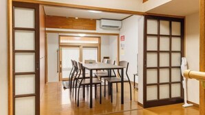 A traditional Japanese room with tatami flooring, a low table with chairs, and shoji screens.