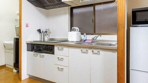 A compact kitchen with white cabinets, a built-in dishwasher, a microwave, and a sink.