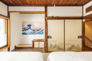 Ein traditioneller japanischer Raum mit Tatami-Böden, einer Shoji-Schiebetür und einem Gemälde einer Welle.