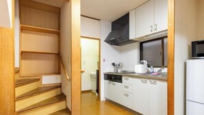 A kitchen with white cabinets, a black range hood, a microwave, and a refrigerator.