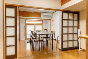 Ein traditioneller japanischer Raum mit Tatami-Boden, einem niedrigen Tisch mit Stühlen und Schiebetüren.