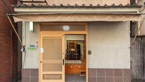 A traditional Japanese entrance with a sliding door, a small porch area, and a tiled floor.