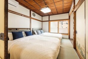 A traditional Japanese room with two beds, tatami flooring, and a shoji screen door. - Asakusa old town guesthouse (Tokyo)