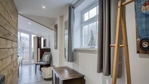 A hallway with a wooden wall, a bench, a small table, and a painting on the wall.