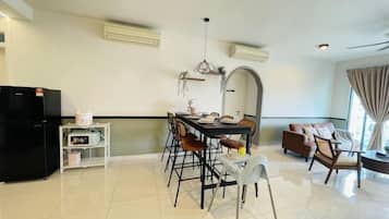 Un salon moderne avec un coin repas, un réfrigérateur noir et un canapé.