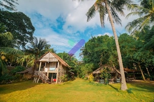 A rural setting with thatched-roof huts surrounded by lush greenery and palm trees.