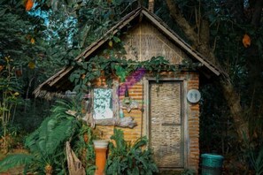 A rustic wooden cabin with a thatched roof, surrounded by dense foliage. - Bunga Jabe (Karimunjawa)