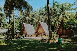 A tropical resort with thatched-roof cottages surrounded by palm trees.