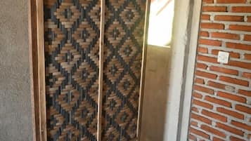A doorway with a patterned wooden screen and a brick wall.