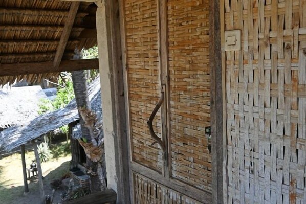 Une structure traditionnelle en bois, dotée d’un mur en osier tressé et d’un toit de chaume.