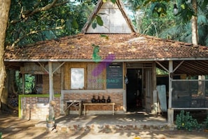 A rustic wooden structure with a tiled roof, a bench, and a table in front. - Bunga Jabe (Karimunjawa)