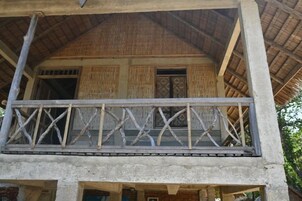 Un edificio con balcón, techo de paja y estructura de hormigón.
