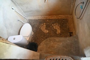 A bathroom with a white toilet, a shower area, and a visible drain. - Bunga Jabe (Karimunjawa)