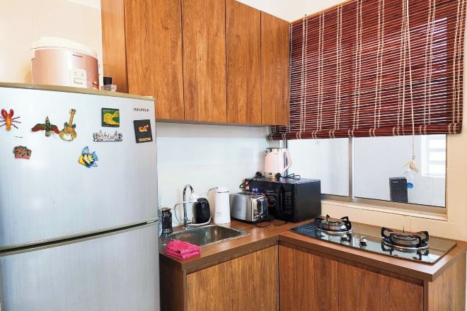 Una cocina compacta con armarios de madera, un refrigerador blanco, una estufa a gas y un microondas.