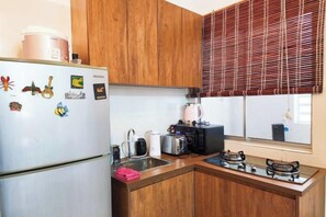 Una cocina compacta con armarios de madera, un refrigerador blanco, una estufa a gas y un microondas.