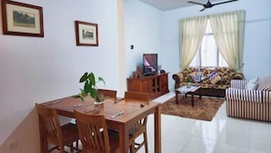 Un comedor con mesa y sillas de madera, un sofá, un televisor y un ventilador de techo.