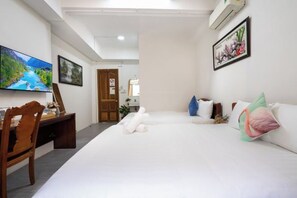 Habitación de hotel con cama, escritorio, silla, televisor y obras de arte en las paredes.