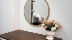 A mirror with a wooden frame, a small white vase with flowers, and a wooden table. - Galaxy Bui vien Street Home (Ho Chi Minh City)