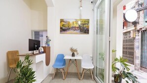 A reception area with a desk, computer, chairs, and a painting on the wall. - Galaxy Bui vien Street Home (Ho Chi Minh City)