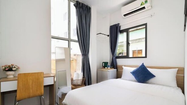 A hotel room with a bed, a desk, a chair, an air conditioning unit, and a window with curtains. - Galaxy Bui vien Street Home (Ho Chi Minh City)
