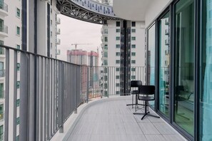 Un balcón con barandilla curva, una silla y vistas a un paisaje urbano con edificios.