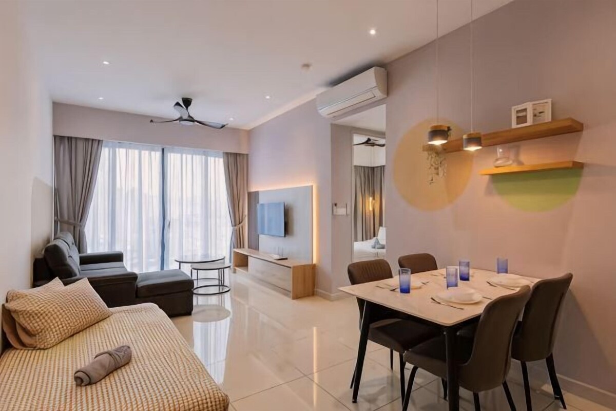 A modern hotel room with a bed, a dining table, chairs, a TV, and a sofa.