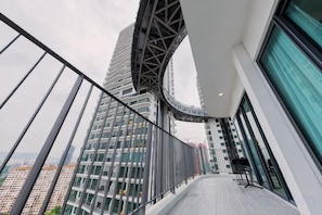 A modern building with a curved glass facade, a balcony with metal railings, and a view of other high-rise buildings.